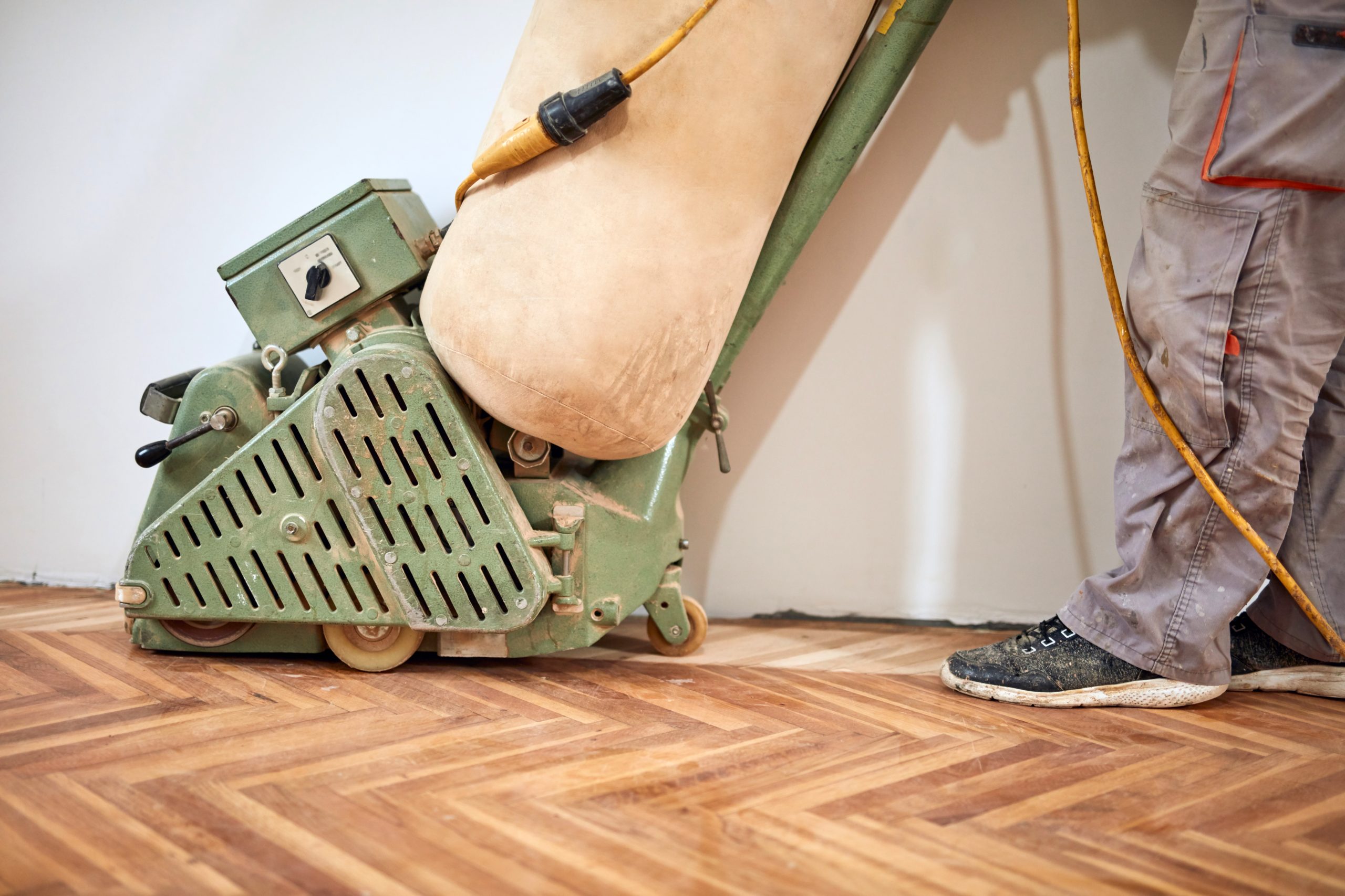 Stanmore Oak Herringbone Parquet — Dust-Free Floor Sanding Close-Up Close-up of a drum sander with integrated dust-extraction bag carrying out Dust-Free Floor Sanding on an oak herringbone parquet floor in Stanmore.