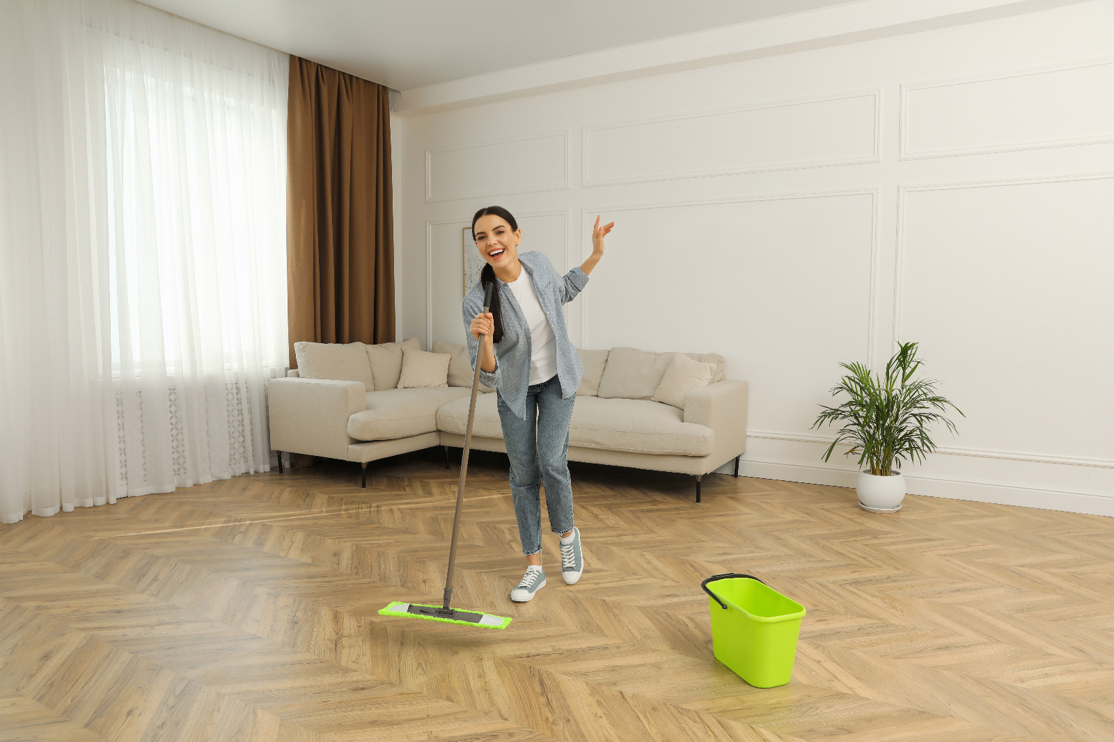 Smiling homeowner cleaning a freshly restored oak herringbone parquet floor in a Stanmore living room after Dust-Free Floor Sanding.