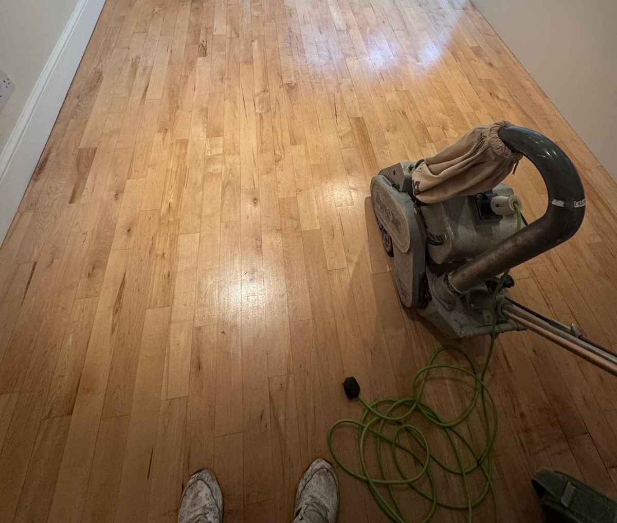Wood Floor Sanding in Stanmore – light oak strip hardwood floor being sanded with a professional drum sanding machine in a hallway.