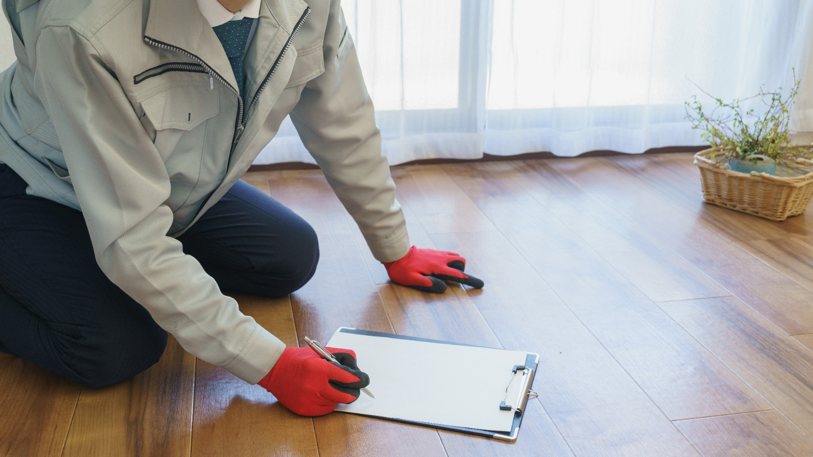 Wood Floor Sanding inspection in Stanmore – specialist assessing a medium-toned oak plank hardwood floor before sanding.