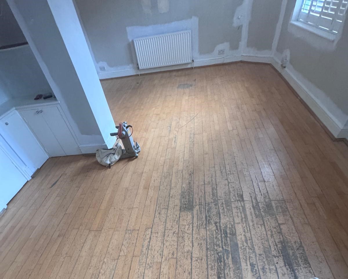 Wood Floor Sanding in Stanmore – worn oak strip hardwood floor in a living room before sanding and restoration.