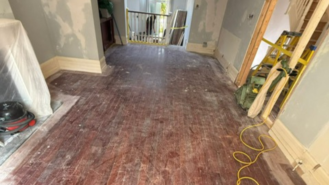 Wood Floor Sanding in Stanmore – tired solid oak strip hardwood floor in a hallway and living area before sanding and restoration.