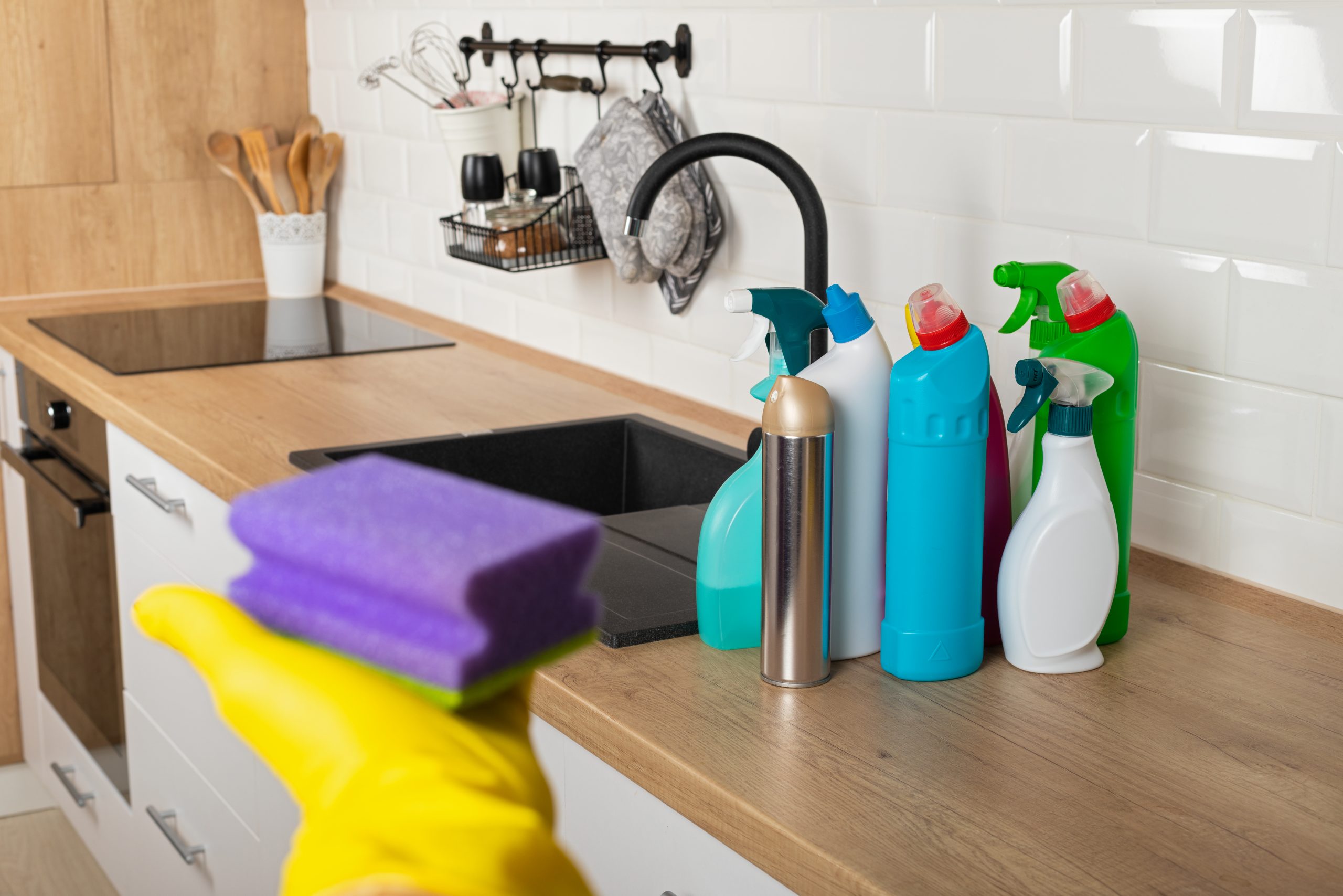 Cleaning products and sponge on an oak-effect laminate kitchen worktop and laminate plank floor in Stanmore, prepared for safe Worktop Refinishing and aftercare.