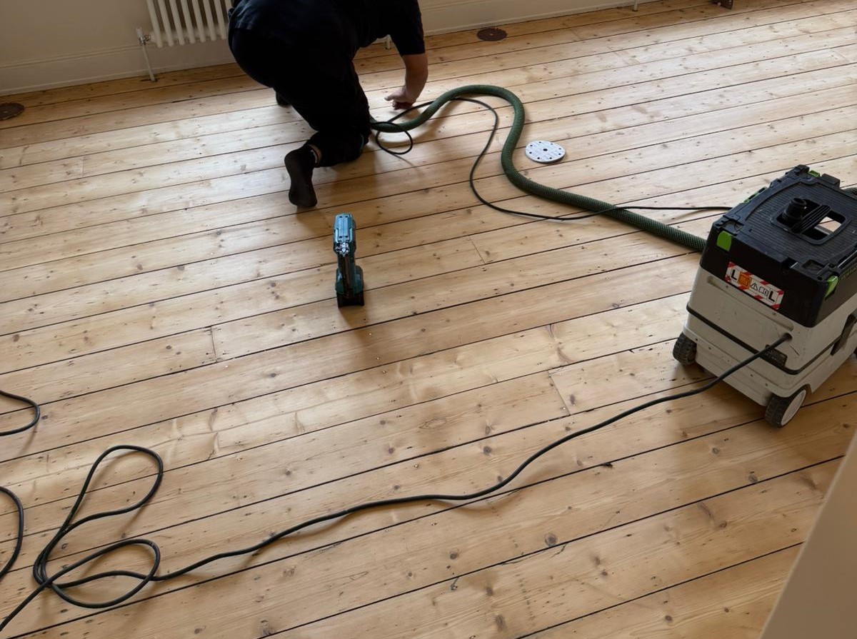 Wood Floor Sanding in Stanmore with dust-free extraction, showing a technician preparing natural pine softwood floorboards for a smooth refinished surface.