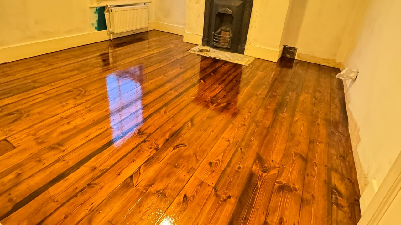 Wood Floor Sanding in Stanmore showing freshly restored pine floorboards with a rich stained, high-gloss finish after sanding and sealing.